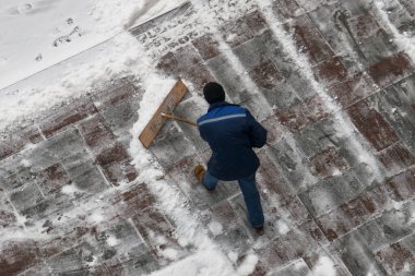 Bir kar yağışı sonrası sokakta kürekle kar temizleyen bir belediye çalışanı.