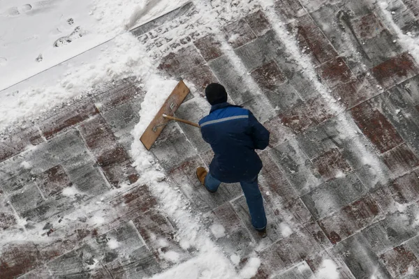 Městský dělník čistý sníh s lopatou na ulici po sněžení — Stock fotografie