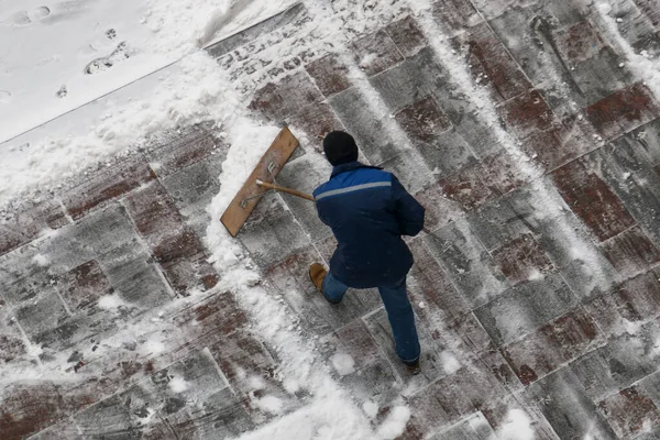 Operaio urbano neve chiara con una pala sulla strada dopo una nevicata — Foto Stock