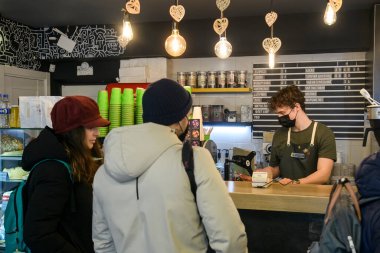Yüzünde koruyucu maske olan genç barista Ukrayna 'nın Kyiv kentindeki kafelerden birinde kahve hazırlıyor..
