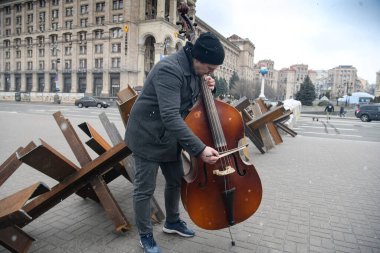 Müzisyen 9 Mart 2022 'de Ukrayna' nın merkezindeki Independence Meydanı 'nda tanksavar savunma inşaatlarında performans sergiliyor. Yüksek kalite fotoğraf