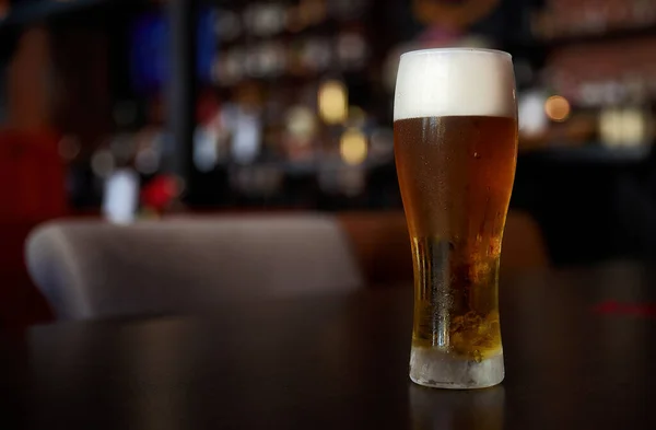 Fresh cold beer, glass of beer on a table in a bar on blurred bokeh background — Stock Photo, Image