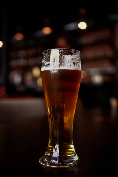 Pohár sört egy asztal egy bárban a homályos bokeh háttér — Stock Fotó