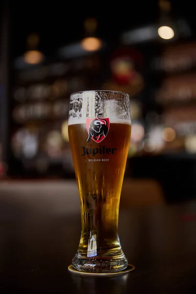 Egy pohár belga Jupiler sört. egy pohár sör az asztalon egy bárban, homályos bokeh háttérrel. Szentpétervár, Oroszország, 19,06,2021 — Stock Fotó