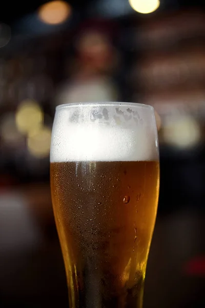 Glass of beer on a table in a bar on blurred bokeh background — Stock Photo, Image