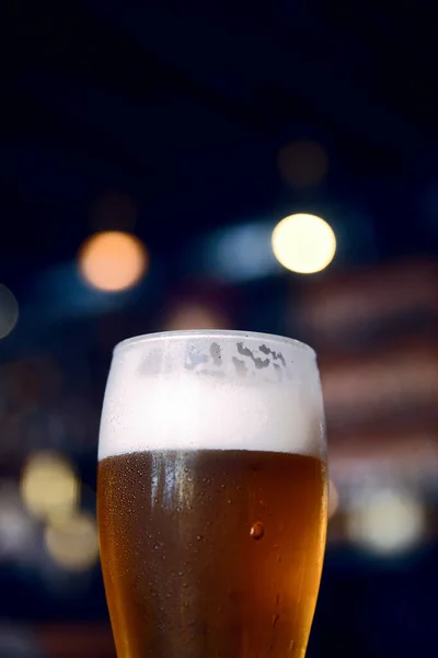 Glass of beer on a table in a bar on blurred bokeh background — Stock Photo, Image