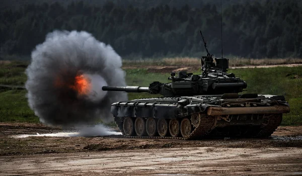 Schoten uit een tankpistool met een rookring, het frame van militaire operaties. Russisch Moderne tank Schieten op een doelwit. Rook, explosie, militaire oefeningen, militaire operaties Stockfoto