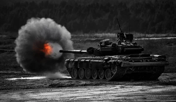 被带着烟圈的坦克炮射杀了，这是军事行动的框架。俄罗斯现代坦克向目标射击。烟雾、爆炸、军事演习、军事行动 图库照片