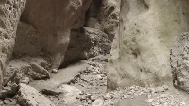 Turistas caminando en el desfiladero, Drone volando a través de un estrecho cañón en las montañas. Garganta estrecha de Karadakh. Belleza de naturaleza intacta. Viajes de espeleología. Dlog-M 10 bits. 24.05.2021, Daguestán, Rusia — Vídeos de Stock