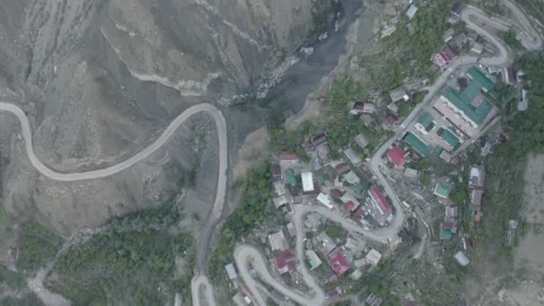 Niesamowity wąż w górach. Widok z lotu ptaka na osadę w górach, zbudowany na krętej drodze. Krajobraz górski, infrastruktura w odległych regionach. Dlog-M 10 bitowy — Wideo stockowe