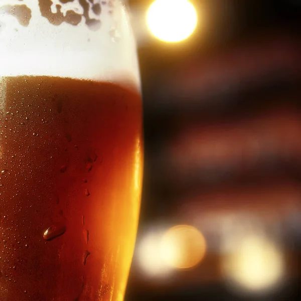 Glass of beer on a table in a bar on blurred bokeh background — Stock Photo, Image