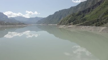 Dağlardaki güzel gölün hava manzarası. Güzel dağ manzarası ve sakin sulardaki yansıma, inanılmaz sahil şeridi ve dağlık arazi. Irganai rezervuarı, Dağıstan. Dlog-M 10 bit