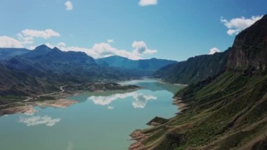 Dağlardaki güzel gölün hava manzarası. Güzel dağ manzarası ve sakin sulardaki yansıma, inanılmaz sahil şeridi ve dağlık arazi. Irganai rezervuarı, Dağıstan. 10 bit Video