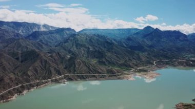 Dağlardaki güzel gölün hava manzarası. Güzel dağ manzarası ve sakin sulardaki yansıma, inanılmaz sahil şeridi ve dağlık arazi. Irganai rezervuarı, Dağıstan. 10 bit Video