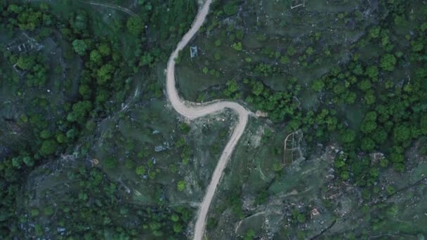 Niesamowity wąż w górach. Widok z lotu ptaka na osadę w górach, zbudowany na krętej drodze. Krajobraz górski, infrastruktura w odległych regionach. 10-bitowy film — Wideo stockowe