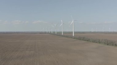 Enerji üretimi için güçlü rüzgar türbini çiftliğinin havadan görüntüsü. Rüzgar güç türbinleri sürdürülebilir gelişim için temiz yenilenebilir enerji üretiyor. Alternatif enerji. 4K, 10 bit, DJI DLog-M profili