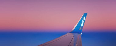 Wing of the FlyDubai airplane during a flight. Winglet of an airliner against the background of the dawn sky. 27.01.2022 Dubai clipart