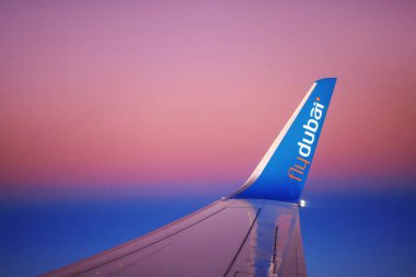 Uçuş sırasında FlyDubai uçağının kanadı. Şafak vakti gökyüzünün arka planına karşı bir uçağın kanadı. 27.01.2022 Dubai