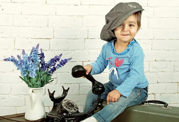 Fille dans une casquette s'assoit sur une valise — Photo