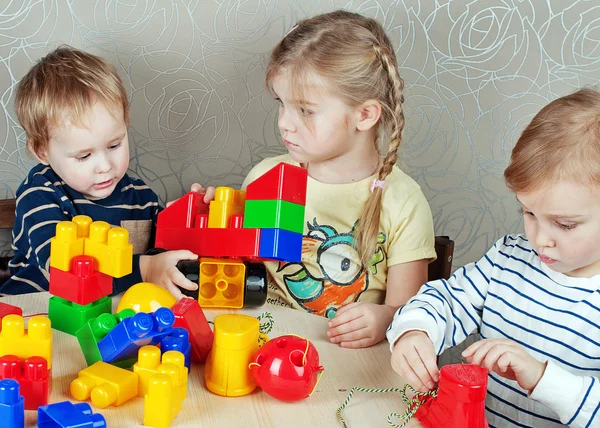 Three children playing with toys — Stock Photo, Image