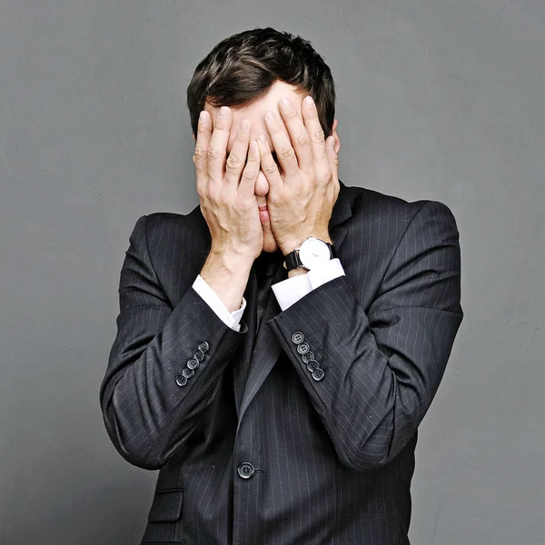 Young man hides his face on a gray background — Stock Photo, Image