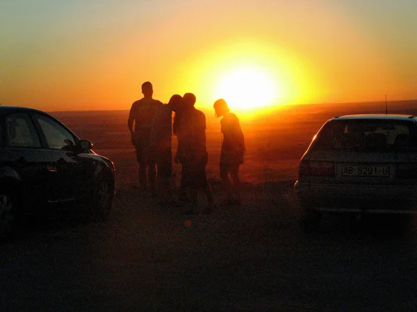 Silhouetten von Autos und Menschen bei Sonnenuntergang — Stockfoto