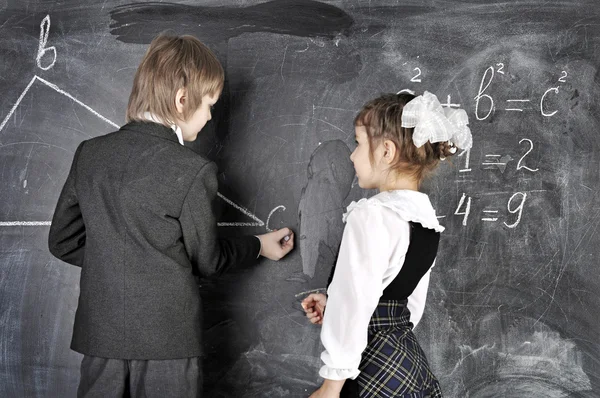 Boy and girl writing on blackboard — Stock Photo, Image