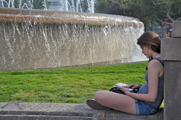 读一本书的喷泉附近的女孩 — 图库照片