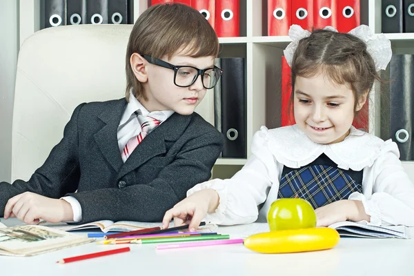 Niño y niña sentados en una mesa en los colegiales con libros —  Fotos de Stock