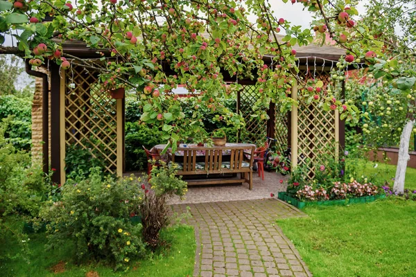 在花园里用苹果树和鲜花打开木制的凉亭 夏季景观背景 图库图片