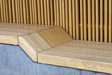 Güneşli bir günde insanların olmadığı boş, modern ahşap banklar, şehir parkında halka açık yerler. Şehir geliştirme, şehir planlama, kamusal alanlar, dinlenme alanları. Şehir halkı dinlenmek için vandal karşıtı mobilyalar