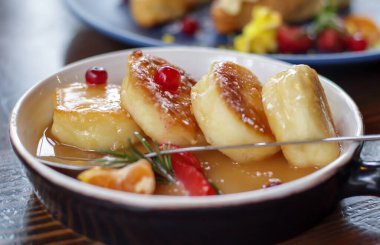 Dört yuvarlak paneer cheesecake 'i, eko tarzında, restoran masasındaki tabakta tuzlu karamel ile kapayın. Cheesecake ya da seramik kasede süzme peynirli krep. Sabah kahvaltısı