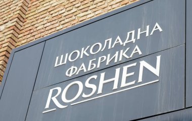 Kiev 'deki Roshen Çikolata Fabrikası' nın ana girişi. Ukraynaca beyaz harfler, siyah bir tabela üzerinde. Roshen şirketinin amblemi. Ukrayna, Kiev - 09 Şubat 2022
