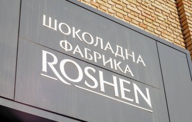 Kiev 'deki Roshen Çikolata Fabrikası' nın ana girişi. Ukraynaca beyaz harfler, siyah bir tabela üzerinde. Roshen şirketinin amblemi. Ukrayna, Kiev - 09 Şubat 2022