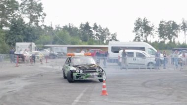 Sürüklenen araba, profesyonel sürücü. Yanan lastiklerden çıkan yoğun dumanlı yarış arabası. Yarış arabası arızası. Rus hareket fiziğinde araba metniyle. Ukrayna, Kiev - 22 Temmuz 2021.