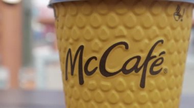 McDonalds 'dan sarı karton kahve fincanı. Mc Cafe kağıt bardak içeceği. Masada bir fincan sıcak çay ya da kahve olsun. Fast food restoranının menüsü. Ukrayna, Kiev - 12 Eylül 2021.