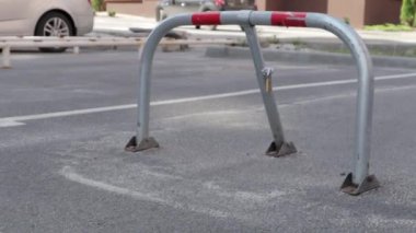 Gri bir park kilidi. Yakın çekim video. Park yeri rezervasyonu, katlanabilir engeller. Otoparkın güvenlik engeli buraya park edilmesini engelliyor..