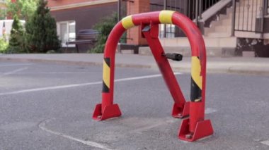 Kırmızı bir park kilidi. Yakın çekim video. Park yeri rezervasyonu, katlanabilir engeller. Otoparkın güvenlik engeli buraya park edilmesini engelliyor..