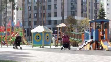 Parktaki bahçedeki renkli, modern çocuk parkında, rahatlatıcı ve oyuncu çocuklar var. Yeşil ağaçlar ve yeni evlerle çevrili bir parkta oyun parkı. Ukrayna, Kyiv - 29 Haziran 2021.