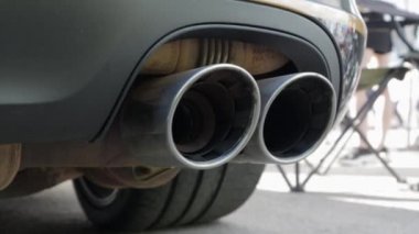 Yeni lüks bir arabanın egzoz sisteminin alt görüntüsü. Panoramik manzara. Zararlı maddeleri motor egzozundan temizlemek ve araç gürültüsünü azaltmak için çift egzoz borusunu kapatın..