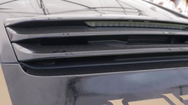 Yansıtıcı siyah boyalı parlak bir Porsche 911 spor araba. Aktif arka spoyler ve stop lambalarının detayları. Araba temizleme konsepti. Bir araba fuarında spoiler 'ı olan bagajın yakın çekimi..