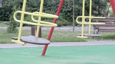 Biri boş, insansız, metal sarısı salıncak açık hava salıncaklarında konut binalarının avlusunda, ileri geri hareket ediyor. Dışarıdaki çocuklar için basit bir serbest atış..