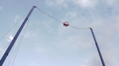 Uçmak tehlikeli bir cazibe. Lastik iplere atlamak. Sıradışı eğlence ve eğlence türleri. Cesur adamları vuran büyük bir mancınık..