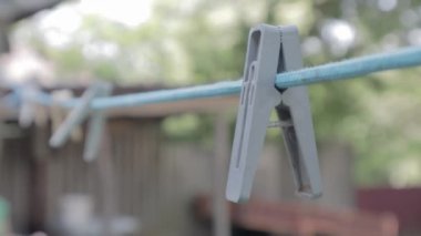 Plastik mandallar ipte bir sırada asılı duruyor. Açık havada, güneşli bir bahçede bulanık bir arka planda. Sokakta çamaşır ipi var. Mandallar..