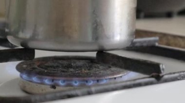 Tencereyi yakın çekim ateşe verdi. Gaz ocağında tencerede yemek pişirmek. Mutfak ocağında yemek pişirmek için gaz ocağı var. Yanan propan ateşiyle mutfak gaz ocağı. Doğal gaz kavramı.