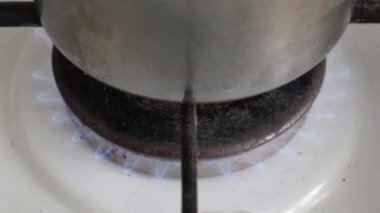Tencereyi yakın çekim ateşe verdi. Gaz ocağında tencerede yemek pişirmek. Mutfak ocağında yemek pişirmek için gaz ocağı var. Yanan propan ateşiyle mutfak gaz ocağı. Doğal gaz kavramı.