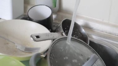 Lavabodaki mutfak aletlerinin yıkanması gerekiyor. Mutfak lavabosunda akan suyla birlikte bir yığın kirli bulaşık. Mutfak aletlerinin yıkanması gerekiyor. Ödev konsepti.