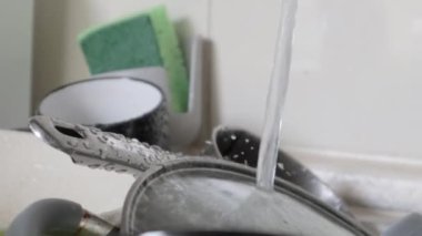 Lavabodaki mutfak aletlerinin yıkanması gerekiyor. Mutfak lavabosunda akan suyla birlikte bir yığın kirli bulaşık. Mutfak aletlerinin yıkanması gerekiyor. Ödev konsepti.
