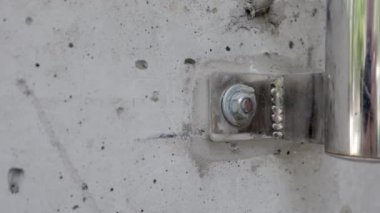 Beton duvar makro sürgüsü stok görüntülerini kapatın. Beton bir duvara cıvatalı krom kaplı bir korkuluk dayamak. Diğer cıvataların yanındaki betona vidalanmış. Gri metalik.