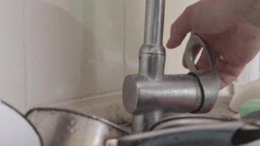 Mutfakta bulaşıkları yıkamadan önce bir adamın eli musluğu açar. Kirli tabaklar, kâseler ve kupalar metal bir lavaboda. Kaotik mutfak sahnesi. Akan su, kapat. Yemekten sonra temizlik..